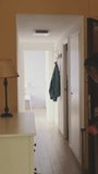 VERTICAL VIDEO: Senior, tired, returns home from trip with suitcase, closes the door and looks at himself in the mirror