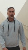 Vertical video, Middle-aged man in sportswear walks along the passage after jogging