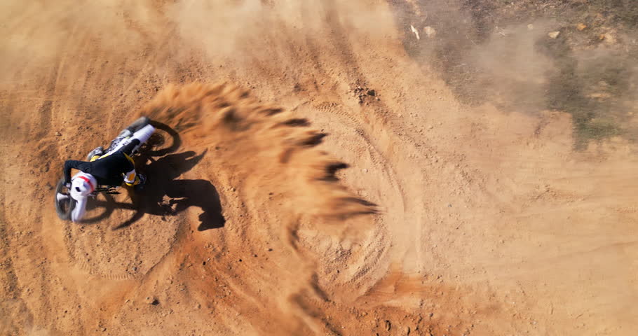 Desert, bike and winner in extreme sports for adventure, fitness or adrenaline with dust in countryside. Motorbike, freedom or athlete person for speed, challenge or victory in sand from drone view
