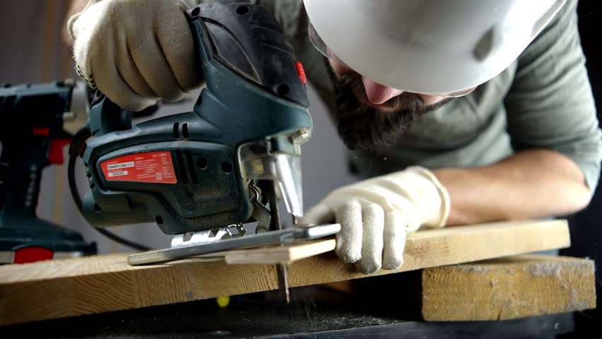 Power Tool. Carpenter Sawing Wood Electric Jigsaw Tool. Carpenter Sawdust Woodwork Jig Saw Tool. Cutting Wood Electric Jig Saw. Craftsman Carpenter Cut Wood. Worker Sawing Jigsaw Power Tool Woodwork