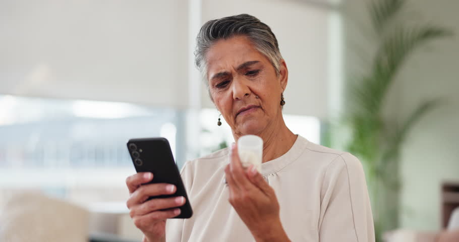 Woman, smartphone and search in home with pills, check on digital app or website for medication information. Mature, curious and female person reading warning label, medicine and medical ingredient