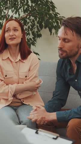 Vertical Screen: Woman wipes away tears during therapy session while her partner speaks, emotional release and communication. Open communication in couple therapy