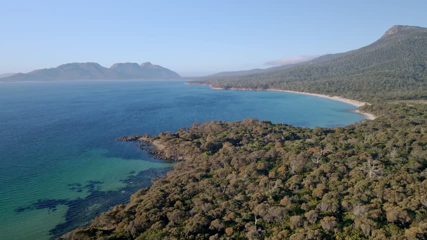 Drone shot of landscape of Freycinet National Park with a dense forest in foreground in Tasmania, Australia.