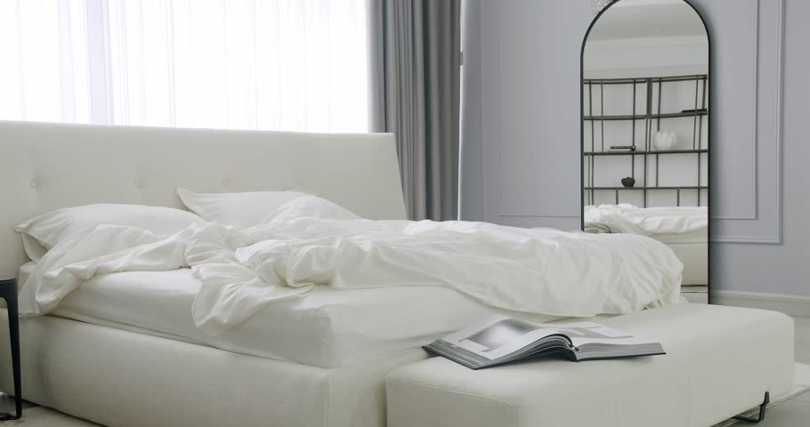 Modern Hotel Bedroom Interior and duble bed with many pillows. Minimalistic scandinavian style of interior. Elegant and Simple Bedroom With a White King Sized Bed. Real Estate.Elegance interior design