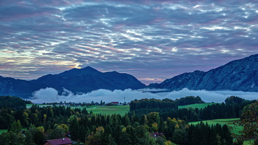 Mist and moody clouds move over Alps in Austria during sunrise timelapse
