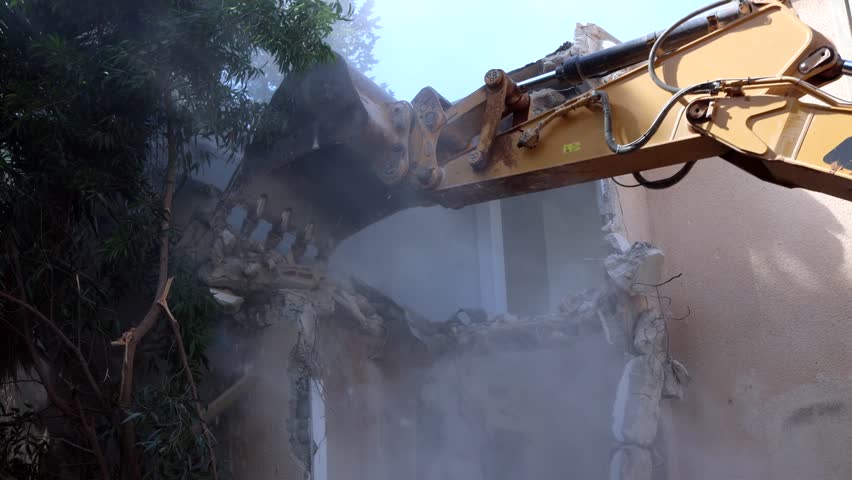 Excavator arm demolishing an old building, Aerial view