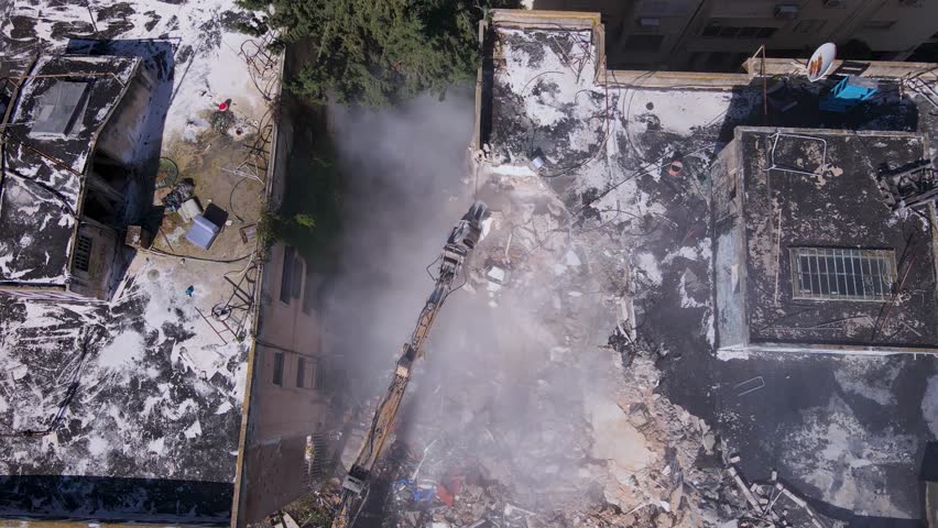 Drone top down pan above building demolition with heavy machinery at construction site