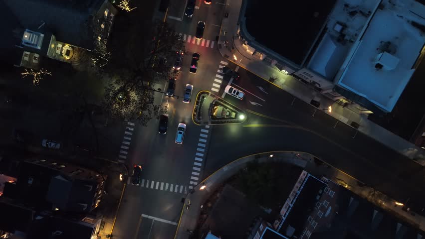 American town square at night. Aerial top down shot spinning above traffic after dusk.