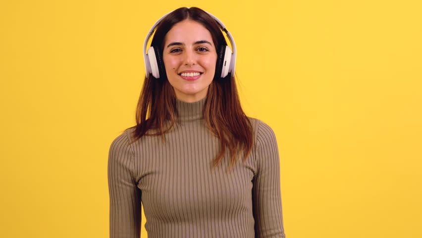 Greeting of smiling young woman on video call on yellow background.