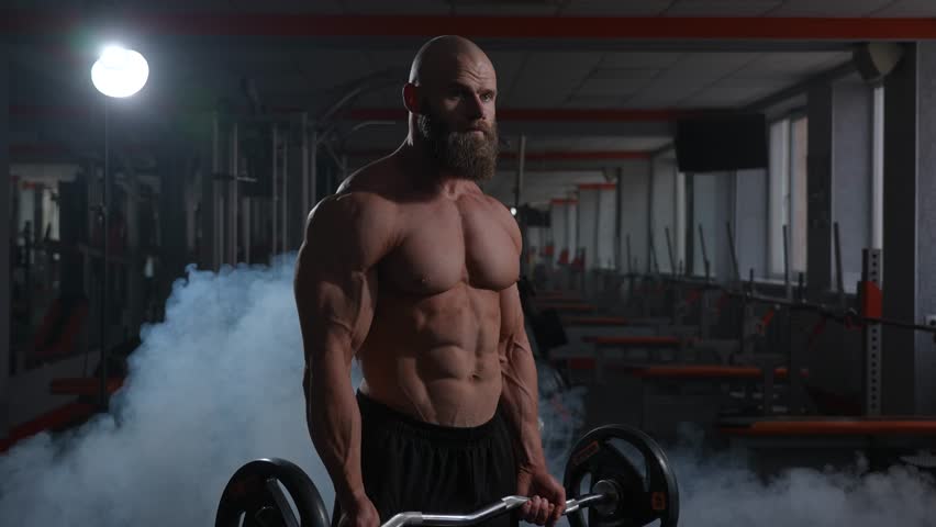 Caucasian bald topless man doing an exercise with a barbell in the gym. Bicep curls with weights. Royalty-Free Stock Footage #3477314703