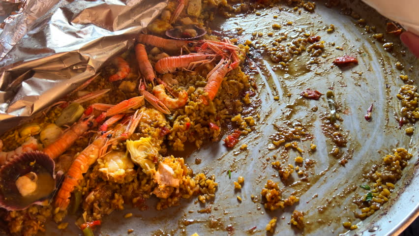 Scooping a traditional Spanish seafood Paella dish with shrimps, St Jacques scallops and Cigala Norway lobsters Nephrops norvegicus, cooked rice with seafood, Marbella Spain, 4K shot