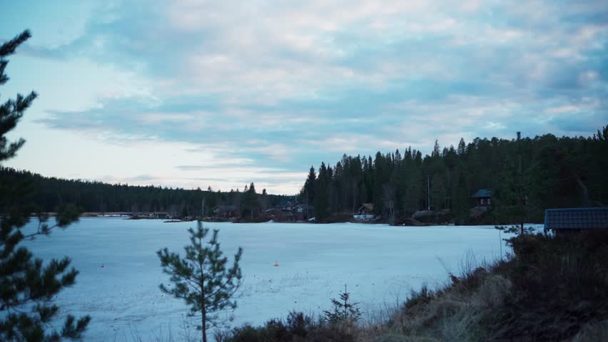 Cloudy Sunset Sky Over Frozen Lake In Rural Farm Landscape In Norway. timelapse