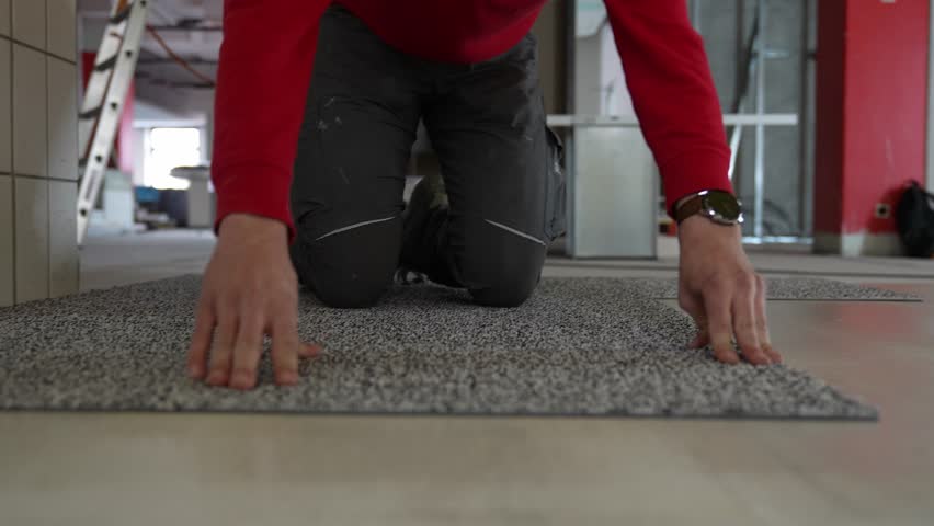 Carpet tiler man laying and installing carpet rug floor wall to wall