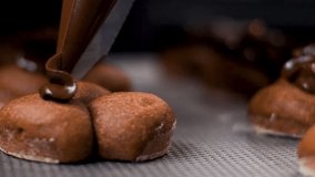 Close up slow motion clip of melted chocolate being piped onto round biscuits on metal baking tray