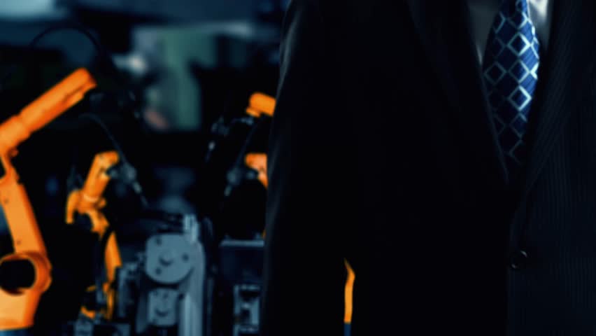 XAI Engineer use cybernated robotic software to control industry robot arm in factory. Automation manufacturing process controlled by specialist using IOT software connected to internet network.