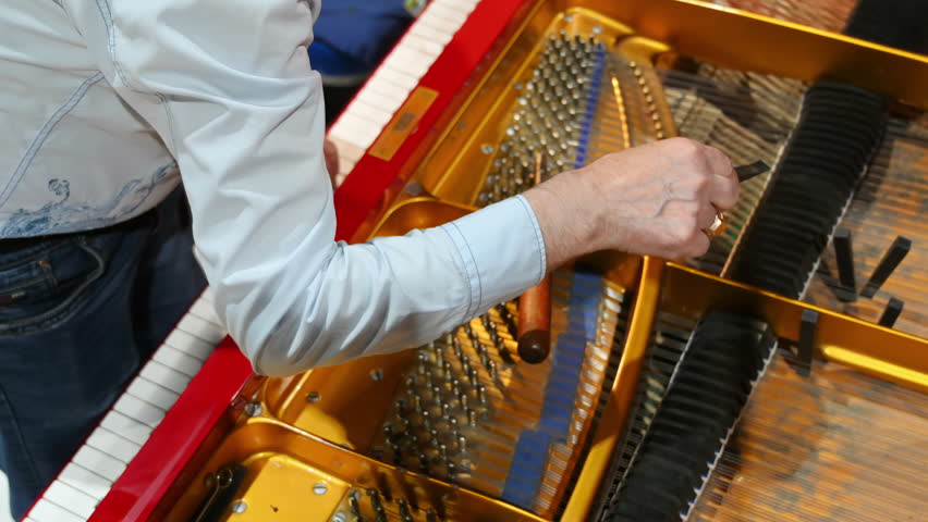Close up of a man fixing a red piano