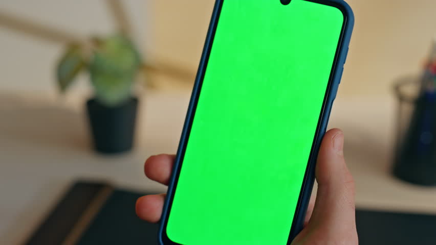 Unknown freelancer using mockup cell working remotely at home closeup. Manager looking smartphone reading electronic book online. Unrecognizable man watching chroma key telephone screen at workplace