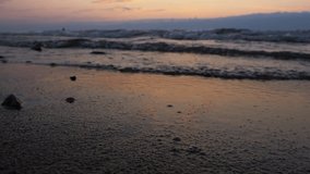 Beautiful sunset on the sea coast. The camera is very close to water and sand. The focus is at the very nearest point.