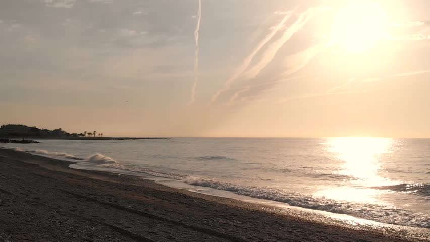 A stunning view from above of the sunrise over the sea, the waves rushing onto the shore. drone video approaching the Mediterranean coast as the sun rises, slow motion. Dawn over the ocean. Solar path