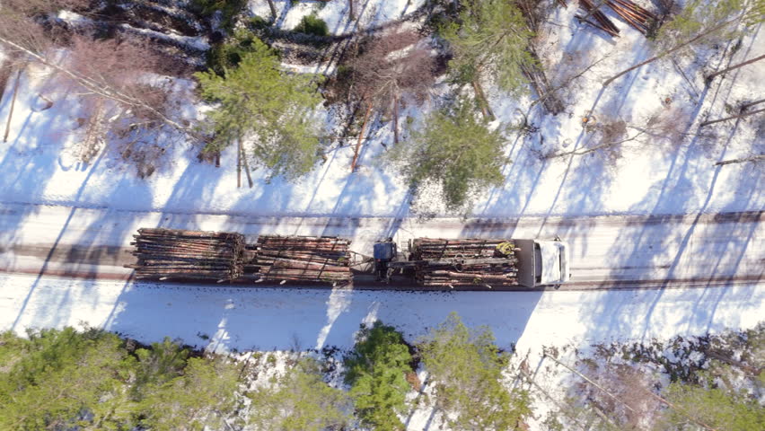 Truck transports felled tree logs on snowy rural track. Overhead aerial tracking Royalty-Free Stock Footage #3477481833