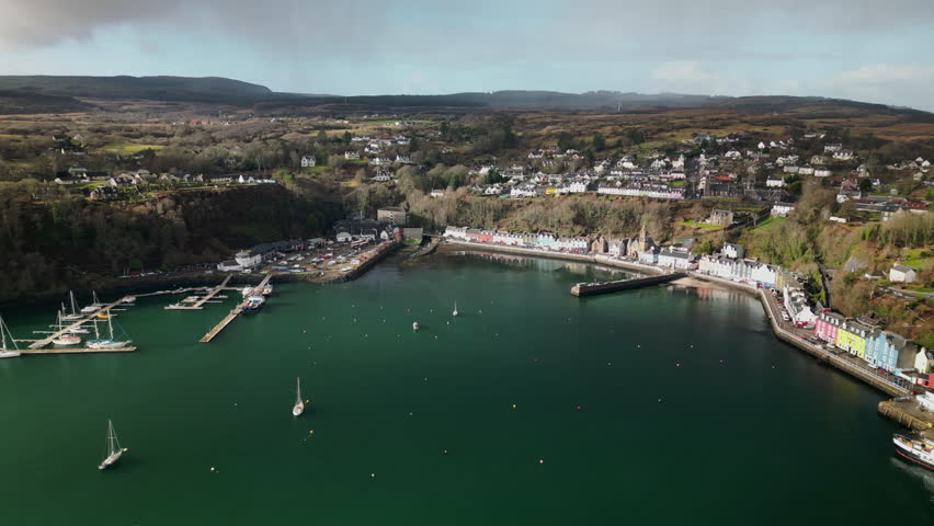 Lateral Linear Aerial of Majestic Port of Tobermory Surrounded by Hills and Trees Royalty-Free Stock Footage #3477554639