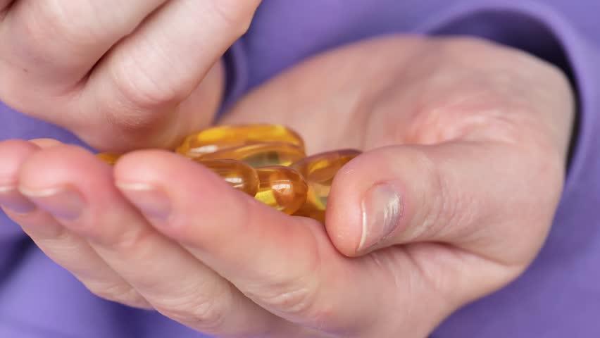 Fish oil.Omega fatty acids jelly capsules.Fish oil capsules in female hands.Healthy fats and womens health.Dietary supplements and vitamins in womens nutrition. Fish oil for womens health.