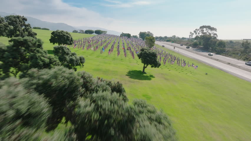 A drone swiftly traverses the sky, offering a poignant view of the Pepperdine memorial flags, a serene tribute to 9.11. Footage 4K. 