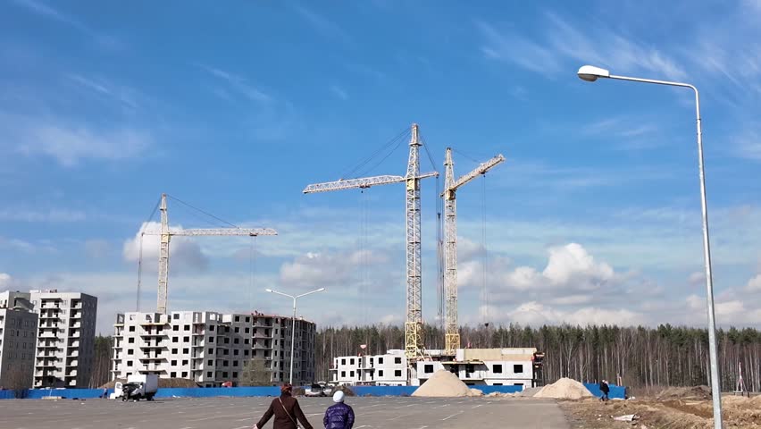 Large construction site with multiple cranes on blue sky background with clouds Royalty-Free Stock Footage #3477650553