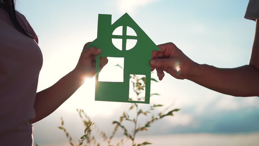 Family mortgage concept. Family holds paper house with their hands at sunset. Family house on loan. Paper house is symbol of family happiness.Housing and mortgage crisis.Dream concept of buying house Royalty-Free Stock Footage #3477692801