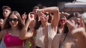 Women and men posing, dancing and flirting on camera at summer pool party in colourful bikinis and sunglasses. Friends enjoying vacation at beach club resort with pool and sun loungers. - Powered by Shutterstock - Get 15% off with code: PIKWIZARD15