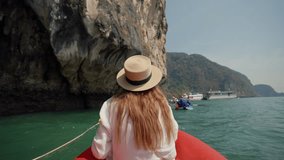 Woman sitting on boat passing lagoon. Back view female travel, riding on gondola, sitting on ship bow and looking take a photo of nature in a wicker hat in summer day. Tourism, enjoyment lifestyle.