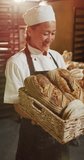 Vertical video of portrait of happy asian female baker with bread in bakery. global business and bakery.