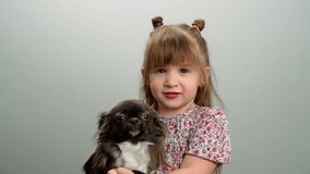 Close-up of a smiling Caucasian girl holding a dog in her arms. Hugs of tenderness and friendship with animals and pets of the child happy childhood. High quality FullHD footage