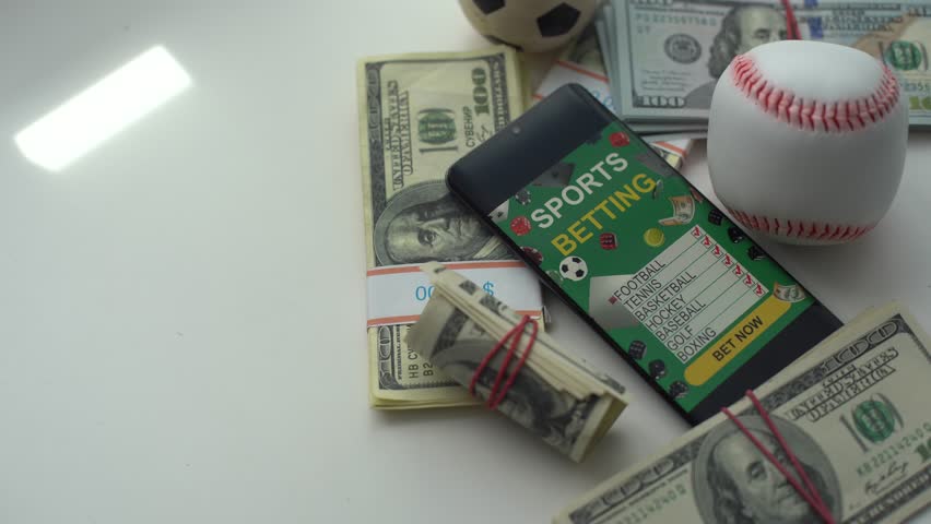Smartphone with gambling mobile application and soccer ball with money close-up. Sport and betting concept