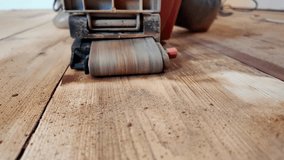 Dynamics of wooden floor restoration. The work of a sander to remove old floor paint. Renovation of the wooden surface. Modern renovation, Sanding a floor with a grinding machine close-up video.