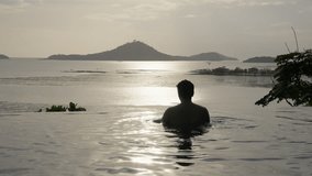 Silhouetted of a man in an infinity pool, captivated by the vibrant hues of the setting sun. waters to the horizon, he enjoys a moment of tranquility, embracing the beauty of nature's spectacle. - Powered by Shutterstock - Get 15% off with code: PIKWIZARD15
