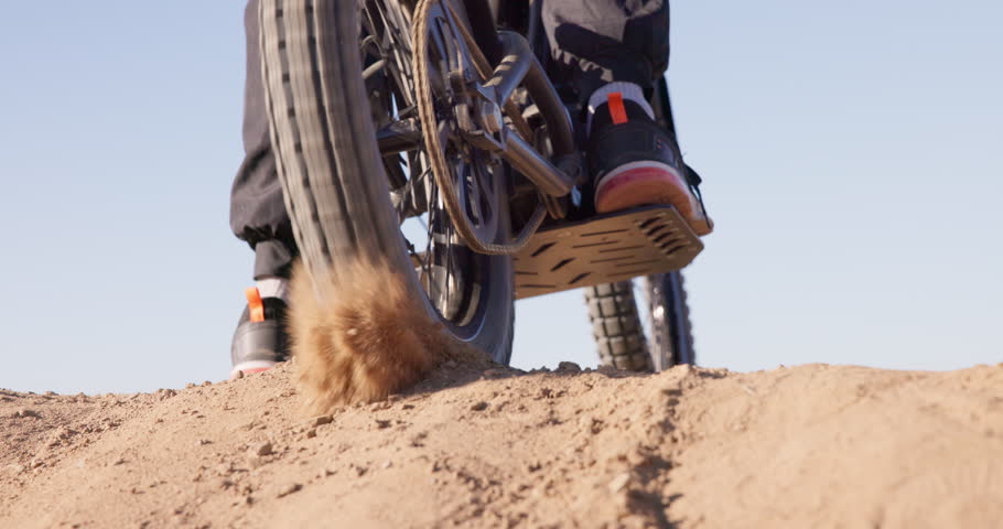 Sport, motorcycle and sand in wheel from desert driving and person with off road stunt on hill. Dirt, trail and fast driver travel on motorbike with skill, technique and moto adventure in countryside