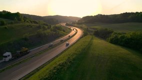 AERIAL, LENS FLARE: Winding highway glows in golden light of setting summer sun. Motorway with smooth flowing traffic winds past green fields and lush forests stretching across the hilly countryside. - Powered by Shutterstock - Get 15% off with code: PIKWIZARD15