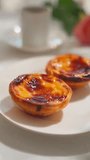 Traditional Portuguese pastry pastel de nata, coffee and roses on a white plate top view vertical video. 4K 