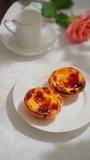 Traditional Portuguese breakfast set: pastry pastel de nata on a white plate, pouring coffee into a cup. Vertical video. 4K 