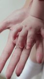 Hand of a newborn. Baby hand in mother hand. Vertical video.