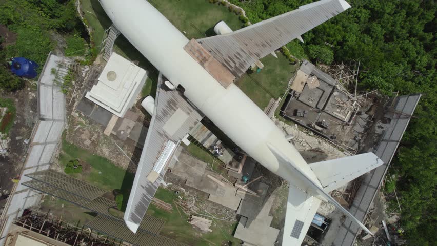A large white airplane is sitting on the ground in front of a house. The scene is eerie and unsettling, as the airplane is not in its usual place, but rather in a residential area