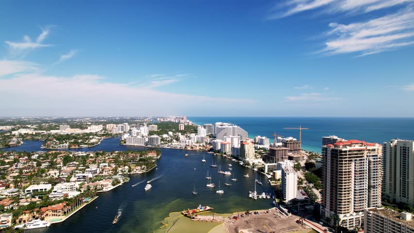 Great aerial drone shot of beach and sand with calm waters buildings on the side blue water blue sky palm trees ft. Lauderdale beach Florida