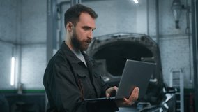 Professional mechanic Caucasian man in uniform male industrial worker technical mechanical engineer using laptop check automobile diagnostics auto system engineering work car maintenance in service - Powered by Shutterstock - Get 15% off with code: PIKWIZARD15