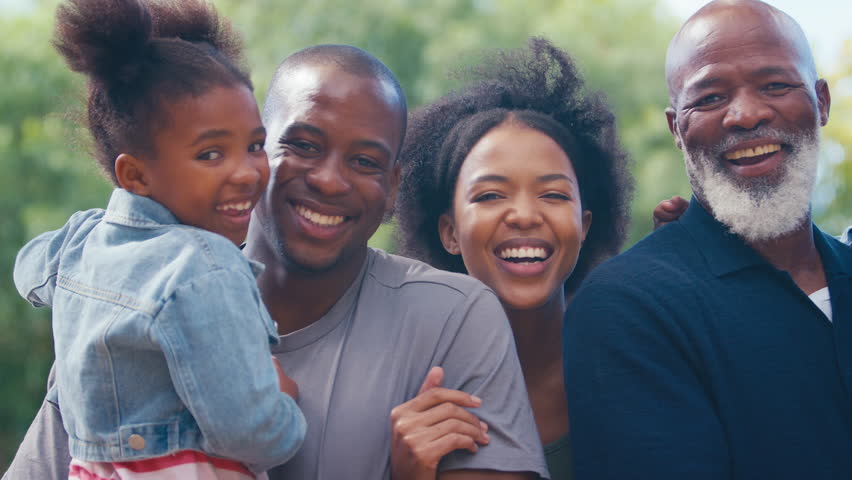 Portrait of three generation family walking outdoors laughing and playing with grandchildren together - shot in slow motion