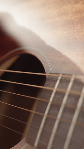 Vertical video. Guitar Lessons for a Woman, Sunlight Illuminating Her, Strings Vibrating with Wave Motions.