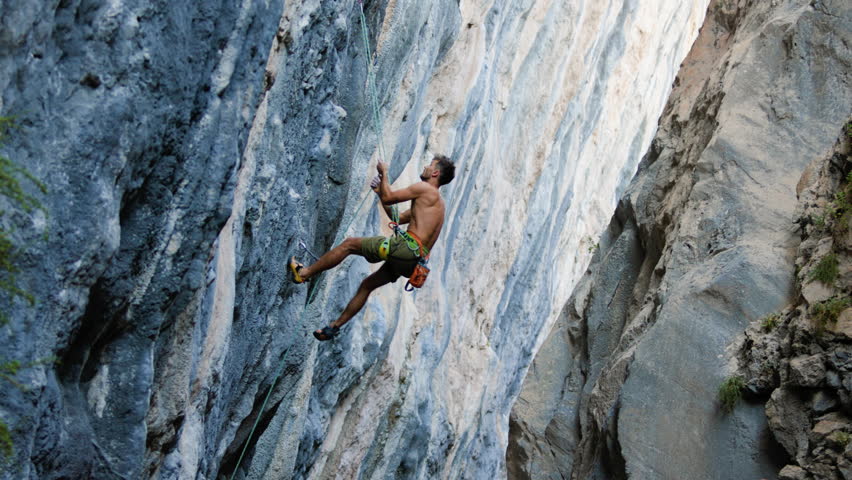 The climber falls and hangs on the rope. rock climber hanging on a rope. A strong man climbs a rock. a person involved in extreme sports, a rock climber training in nature.
