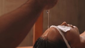 Closeup of pouring oil on female forehead during exotic Shirodhara treatment, Ayurvedic healing technique . Serene young woman at massage session with aromatic oil dripping on forehead and hair. - Powered by Shutterstock - Get 15% off with code: PIKWIZARD15