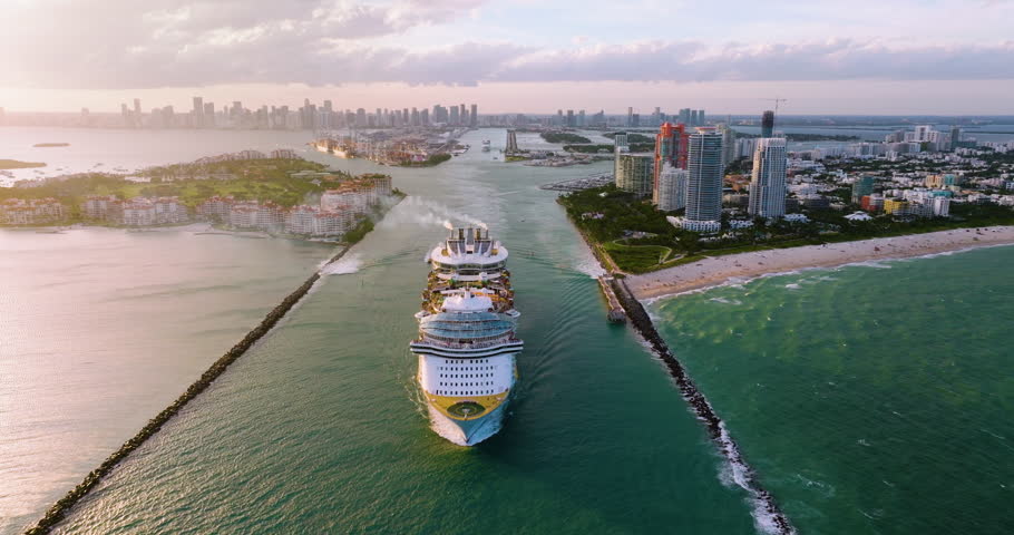 Cruise ship leaving Miami harbor main channel near South Beach. Luxurious hotels and apartment buildings on waterfront and high skyscrapers of downtown district in distance