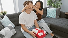 Interracial couple celebrates love with a surprise gift in their cozy living room, sharing a moment of happiness and intimacy. - Powered by Shutterstock - Get 15% off with code: PIKWIZARD15